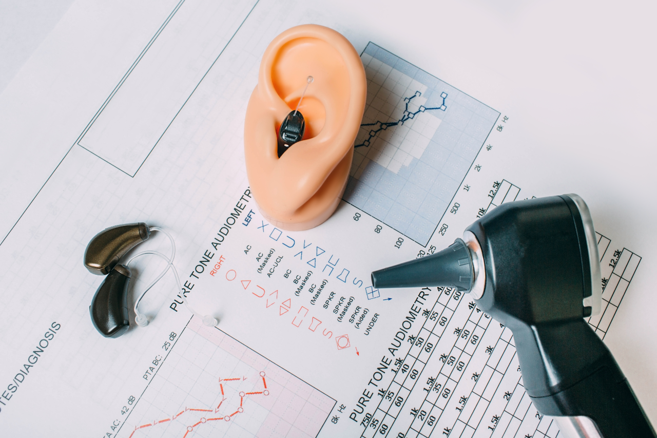 Hearing aids, a model ear pinna and an otoscope rest atop audiogram results