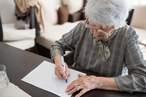 an older lady takes a cognition test using pencil and paper
