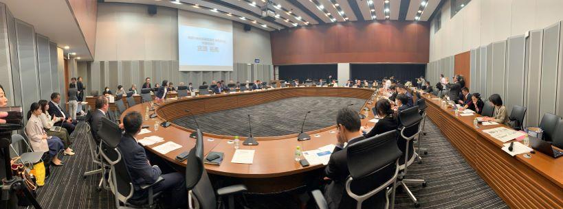 Japanese lawmakers convene around an oval-shaped table for a presentation